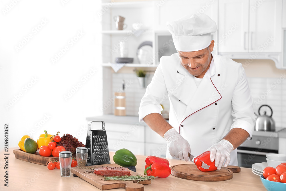 Professional chef cutting pepper on table in kitchen Professional chef cutting pepper on table in kitchen