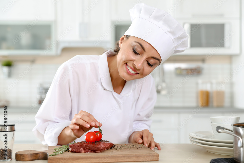 Professional female chef cooking meat on table in kitchen Professional female chef cooking meat on table in kitchen