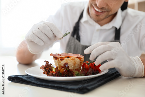 Professional chef presenting dish on table in kitchen, closeup