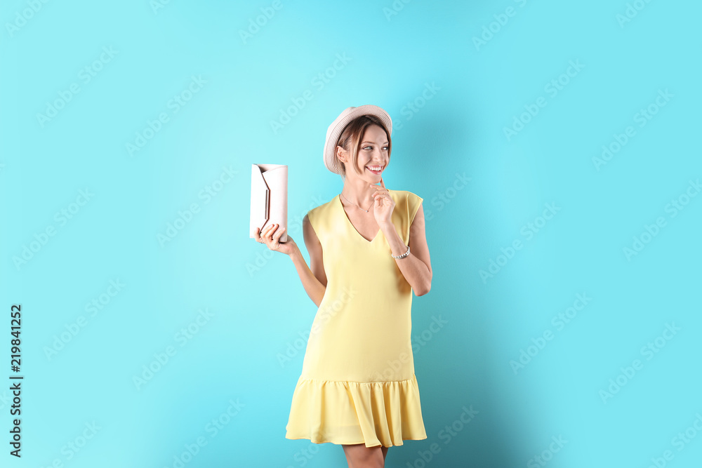 Portrait of young woman in stylish outfit with purse on color background Portrait of young woman in stylish outfit with purse on color background