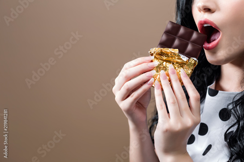 Young woman holding chocolate on a solid background