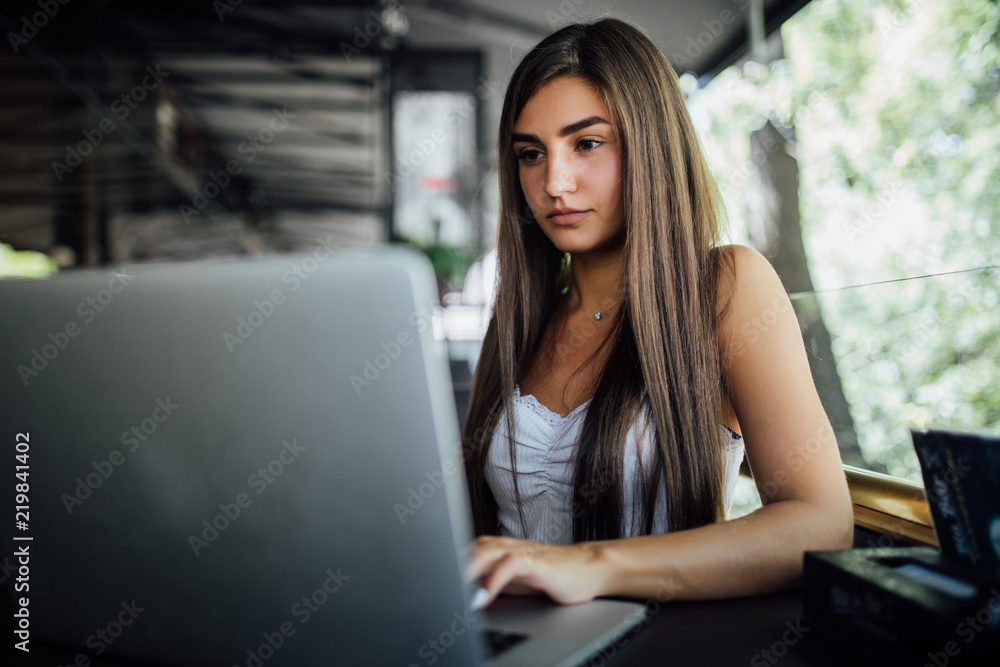 Beautiful woman dreaming about something while sitting with portable net-book in modern cafe bar. Young charming female freelancer thinking about new ideas during work on laptop computer Beautiful woman dreaming about something while sitting with portable net-book in modern cafe bar. Young charming female freelancer thinking about new ideas during work on laptop computer