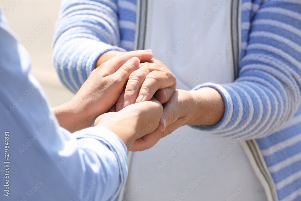Fototapeta premium Helping hands holding together, closeup. Elderly care concept