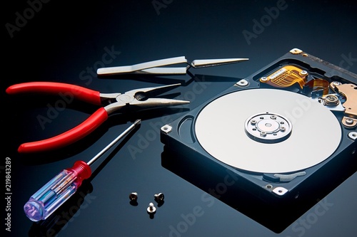 disassembled hard drive and tools are on the operating table