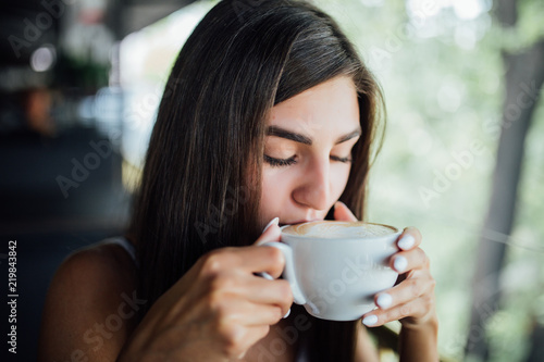 Portrait of young beautiful woman drink coffee sitting in a cafe outdoor summer
