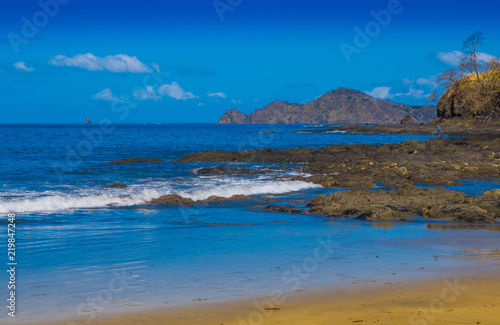 Beautiful outdoor view of of gorgeous rocky beach in Playa hermosa with blue water and beautiful sunny day with blue sky