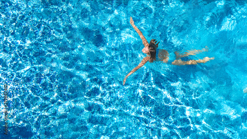 Aerial top view of active woman in swimming pool from above, girl swims in blue water, tropical vacation, holiday on resort concept 