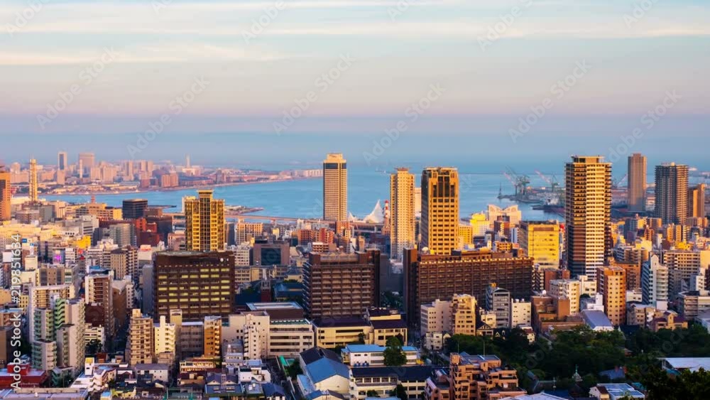 Kobe, Japan. Aerial view of downtown in Kobe, Japan at sunset. Time-lapse of colorful sky with boats at the harbor and numerous skyscrapers. Zoom in