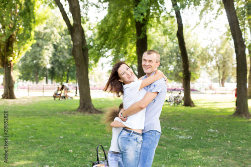 man and woman sitting on the lawn. in a white t-shirt and jeans. a walk in the Park. lover. young couple. summer. family. embrace 