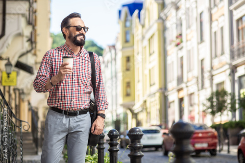 Cheerful adult man drinking coffee in the street