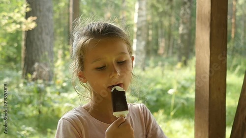 Cute little girl sitting outdoors and eats ice cream 