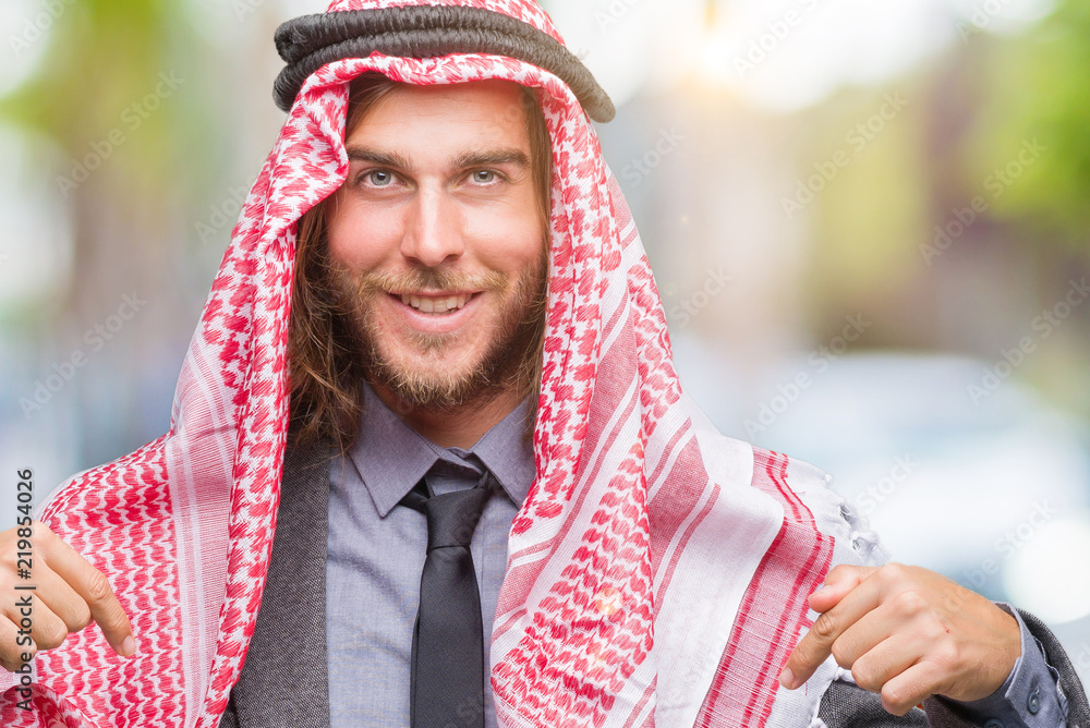 Young handsome arabian man with long hair wearing keffiyeh over isolated background looking confident with smile on face, pointing oneself with fingers proud and happy.