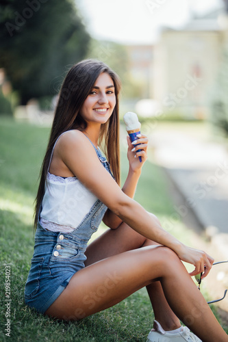Beautiful young woman eating ice-cream sunny day outdoors