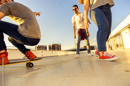 Three friends amuse on rooftop with skateboard © qunica.com