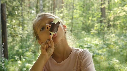 Little girl licking ice-cream. Charming child eats ice cream outdoors.