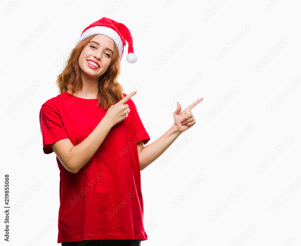 Young beautiful woman over isolated background wearing christmas hat smiling and looking at the camera pointing with two hands and fingers to the side. Young beautiful woman over isolated background wearing christmas hat smiling and looking at the camera pointing with two hands and fingers to the side.