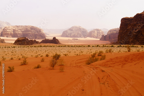 Wadi Rum desert, Jordan, Middle East, known as The Valley of the Moon.  Orange sand, blue sky, haze and clouds. Designation as a UNESCO World Heritage Site. Red planet Mars landscape. photo