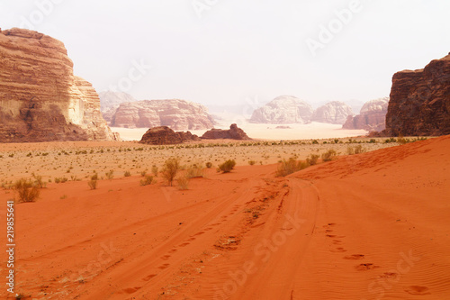 Wadi Rum desert, Jordan, Middle East, known as The Valley of the Moon. Orange sand, blue sky, haze and clouds. Designation as a UNESCO World Heritage Site. Red planet Mars landscape.