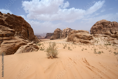 Wadi Rum desert, Jordan, Middle East, The Valley of the Moon. Orange sand, haze, clouds. Designation as a UNESCO World Heritage Site. Red planet Mars landscape. Offroad adventures travel background.