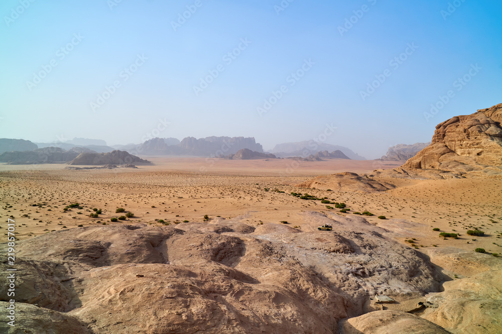 Wadi Rum desert, Jordan, Middle East, The Valley of the Moon. Orange sand, haze, clouds. Designation as a UNESCO World Heritage Site. Red planet Mars landscape. Offroad adventures travel background.