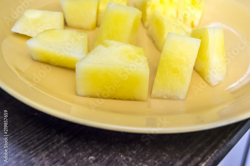 half slices of  yellow watermelon without bones on a wooden background a plate