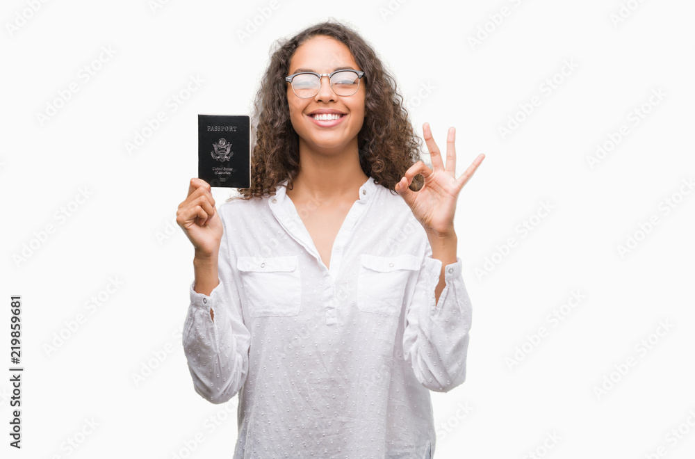 Young hispanic woman holding passport of United States of America doing ok sign with fingers, excellent symbol Young hispanic woman holding passport of United States of America doing ok sign with fingers, excellent symbol