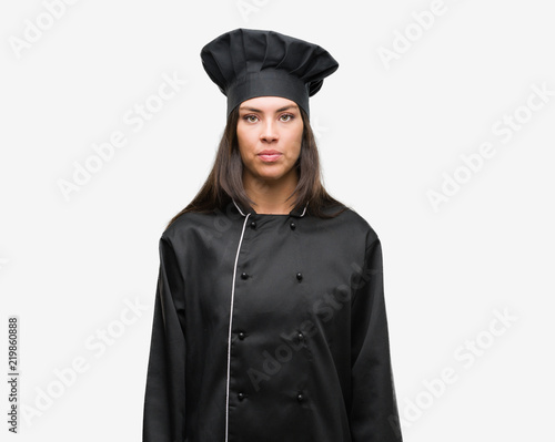 Young hispanic cook woman wearing chef uniform with a confident expression on smart face thinking serious