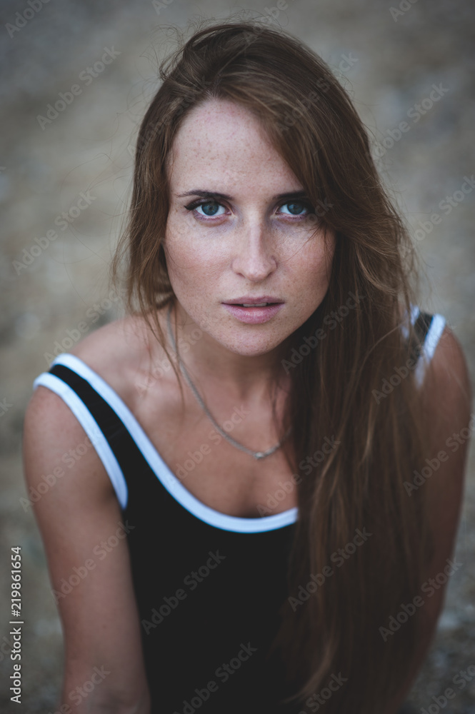 expressive dramatic portrait pretty young woman with freckles in black swimsuit
