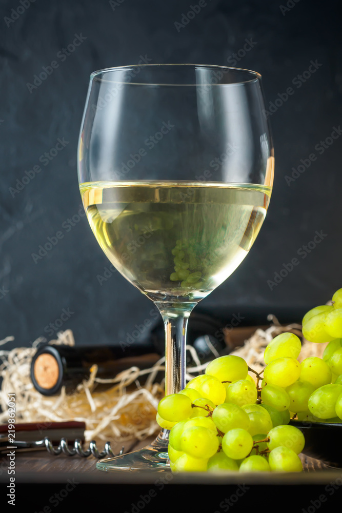 White wineglass and white yellow green bunches of berry grapes with bottle White wineglass and white yellow green bunches of berry grapes with bottle