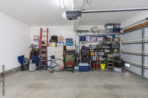 Cluttered but organized clean suburban residential two car garage with tools, file cabinets and sports equipment. 