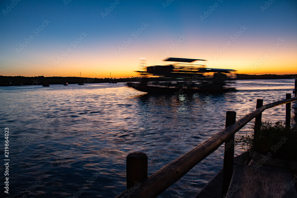 Ferry crossing the river during sunset. Long exposure photography.