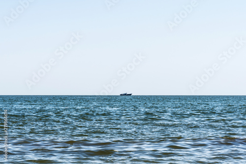 blue sea with waves, far away on a horizon line floating ship, nature abstract background
