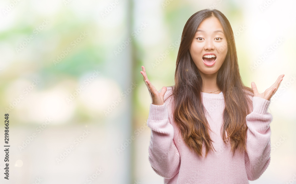 Young asian woman over isolated background celebrating crazy and amazed for success with arms raised and open eyes screaming excited. Winner concept Young asian woman over isolated background celebrating crazy and amazed for success with arms raised and open eyes screaming excited. Winner concept