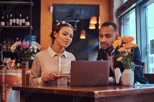 Attractive African-American couple at a business meeting in the restaurant discussing working moments with laptop at lunchtime.