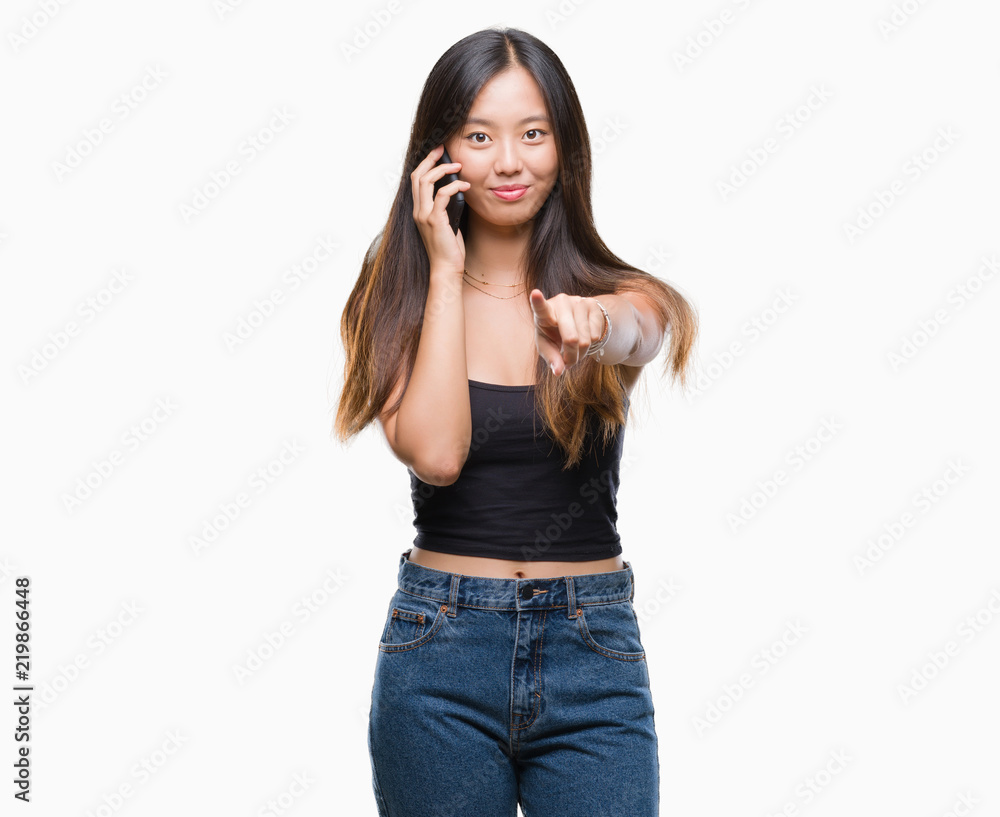 Young asian woman speaking on the phone over isolated background pointing with finger to the camera and to you, hand sign, positive and confident gesture from the front Young asian woman speaking on the phone over isolated background pointing with finger to the camera and to you, hand sign, positive and confident gesture from the front