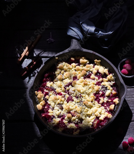 Crumble pie with berries on wooden background.