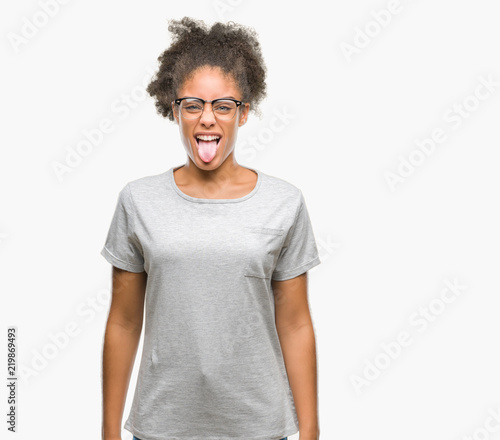 Young afro american woman wearing glasses over isolated background sticking tongue out happy with funny expression. Emotion concept.
