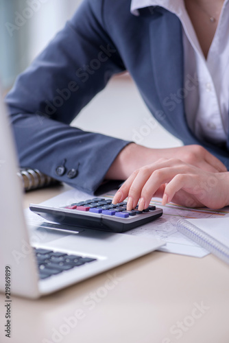 Female finance professional working on keyboard with reports photo