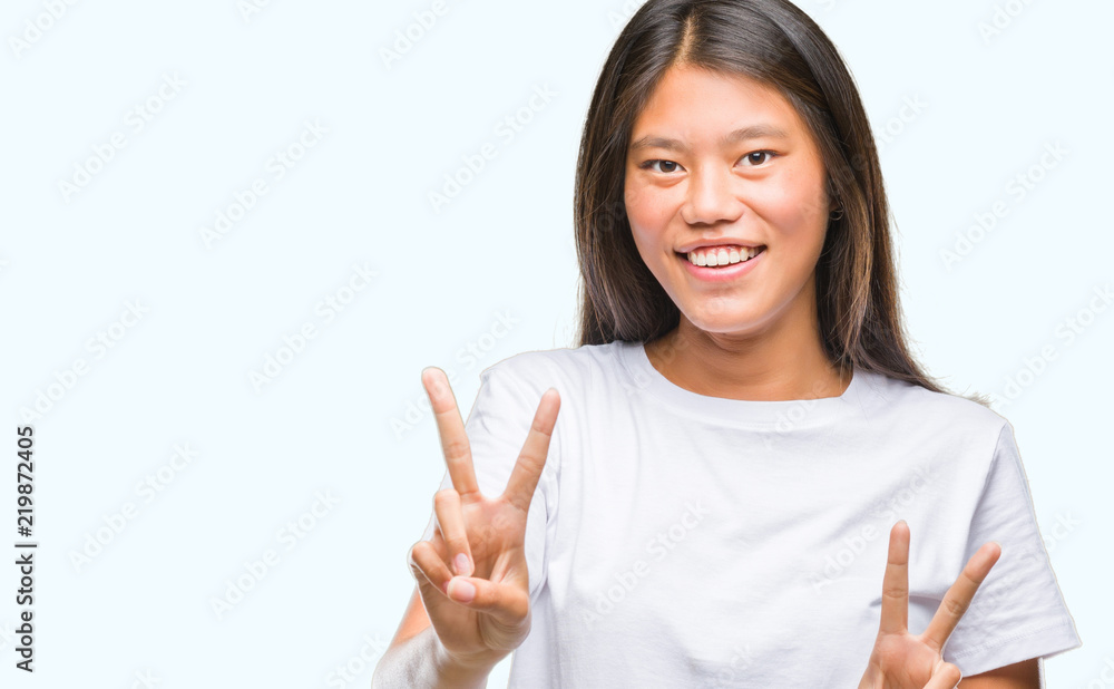 Young asian woman over isolated background smiling looking to the camera showing fingers doing victory sign. Number two. Young asian woman over isolated background smiling looking to the camera showing fingers doing victory sign. Number two.