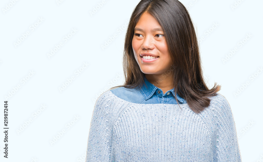 Young asian woman wearing winter sweater over isolated background looking away to side with smile on face, natural expression. Laughing confident. Young asian woman wearing winter sweater over isolated background looking away to side with smile on face, natural expression. Laughing confident.
