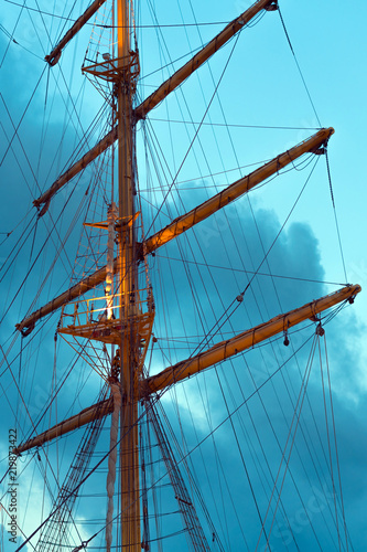The mast of a large sailing ship against the background of the heaven, vertical photo