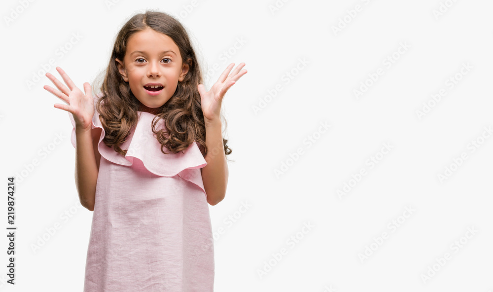 Brunette hispanic girl wearing pink dress celebrating crazy and amazed for success with arms raised and open eyes screaming excited. Winner concept