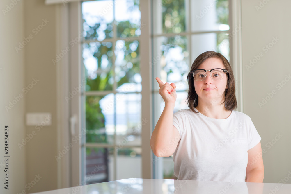 Down syndrome woman at home surprised with an idea or question pointing finger with happy face, number one Down syndrome woman at home surprised with an idea or question pointing finger with happy face, number one