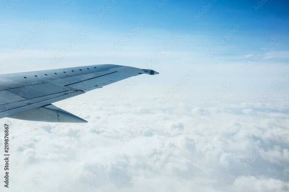 Fototapeta premium Airplane Wing Out of Window with Clouds and Sky