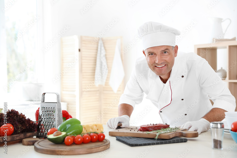 Professional chef cooking meat on table in kitchen Professional chef cooking meat on table in kitchen