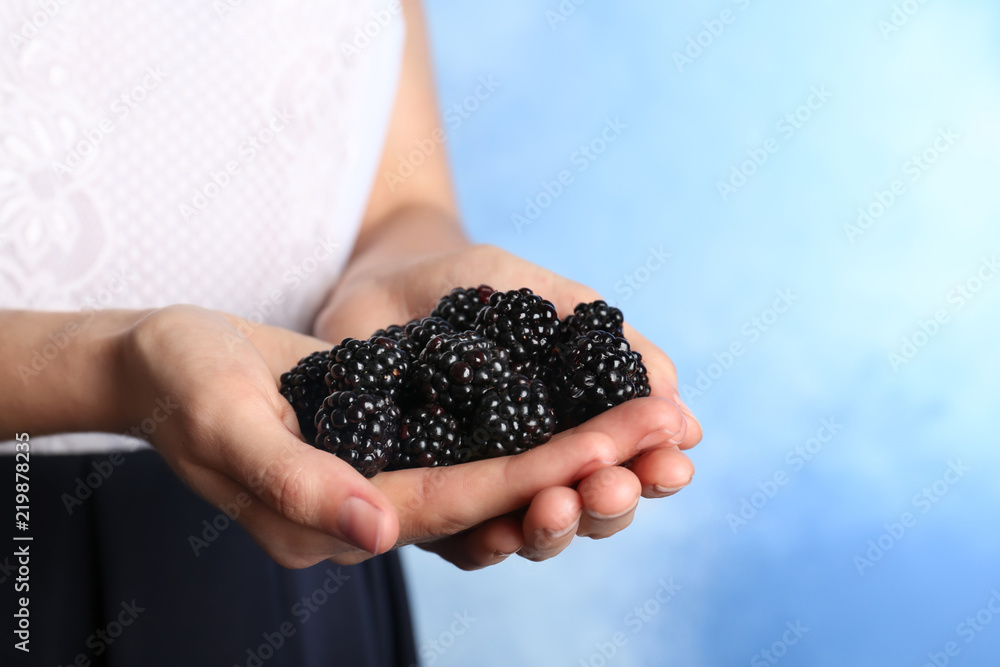 Woman holding fresh blackberry against color background. Space for text Woman holding fresh blackberry against color background. Space for text