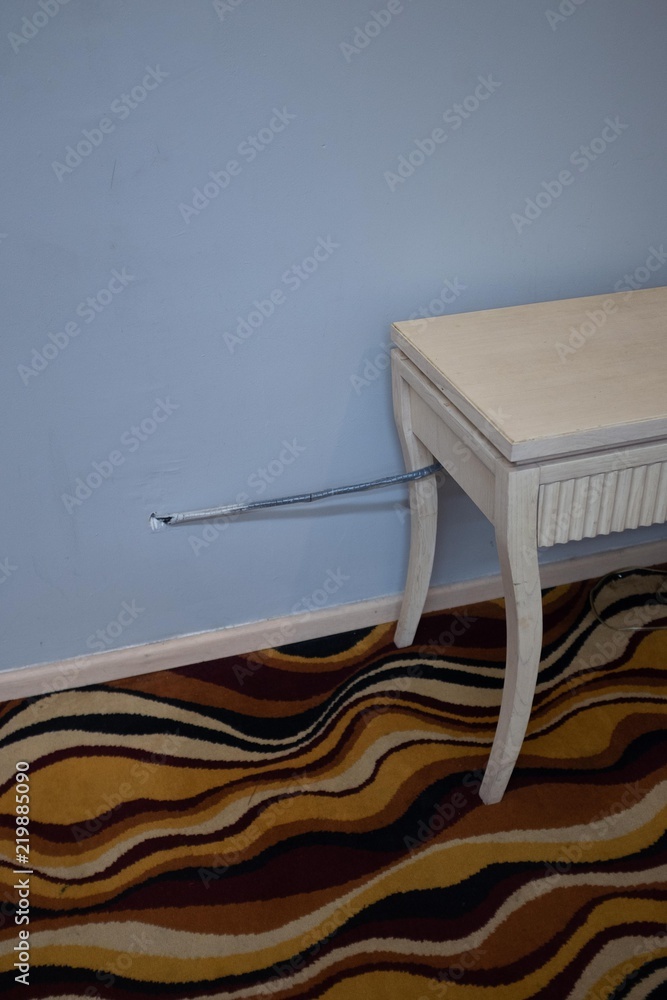 Antique style painted table with cable directly entering a wall