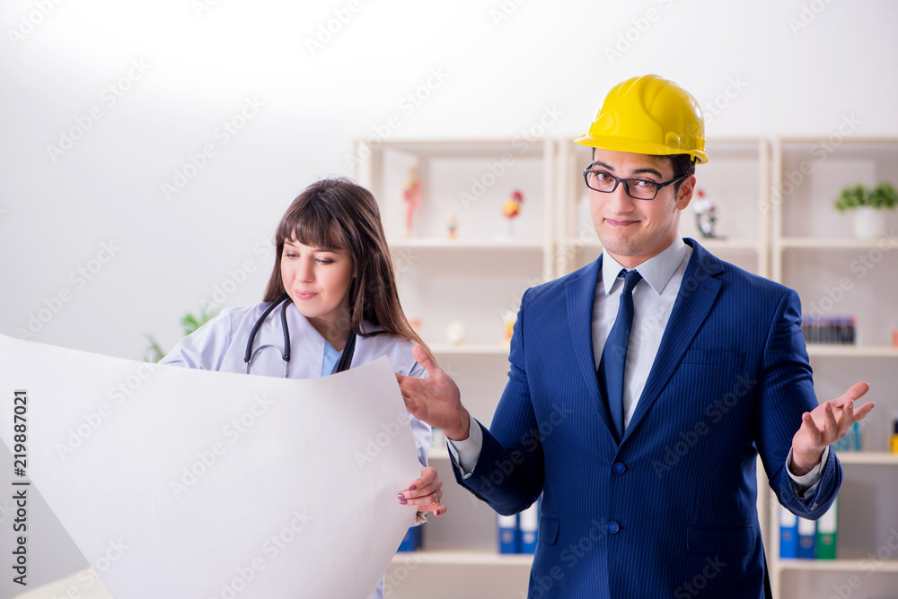 Doctor discussing new hospital plan with architect Doctor discussing new hospital plan with architect