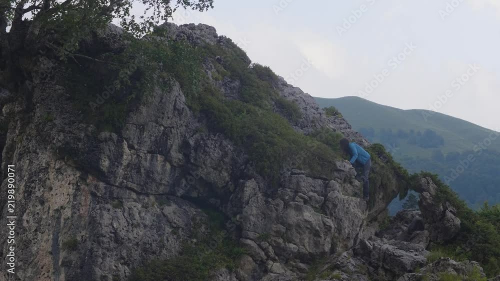 Tourist woman climbing on mountain peak while summer hiking Tourist woman climbing on mountain peak while summer hiking