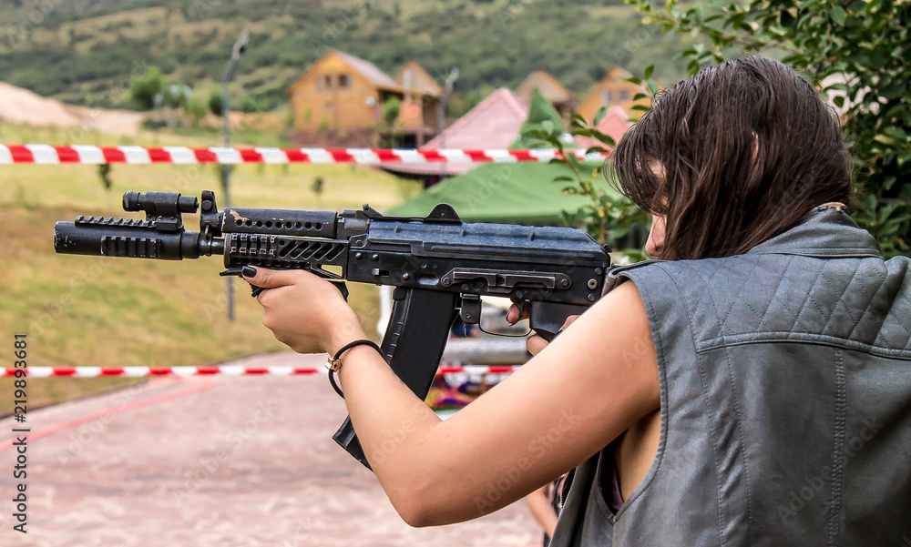 Girl shoots from an automatic weapon outdoors